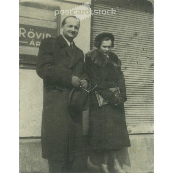 1930-as évek. Napsütésben. Középkorú pár egy rövidárú bolt előtt. Eredeti papírkép. Készítője ismeretlen. (2792221)