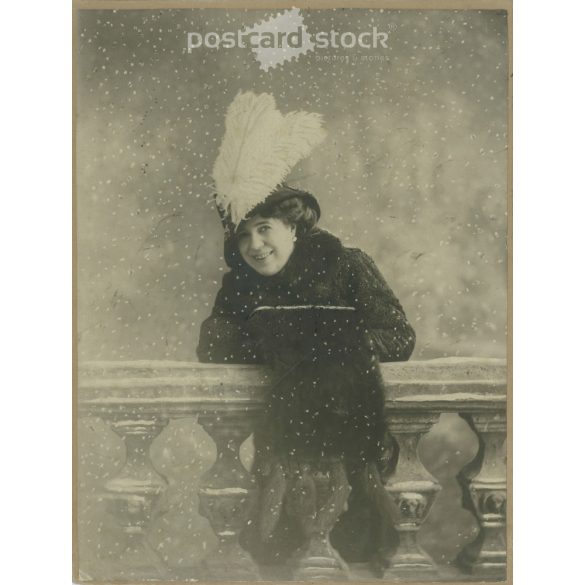 1910-es évek. Elegáns nő, tollas kalapban, hóesésben, műtermi felvétel. Eredeti kasírozott papírkép. Készítője ismeretlen. (2792250)